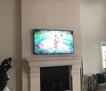 photo of a TV mounted to a residential home wall above an unlit fireplace